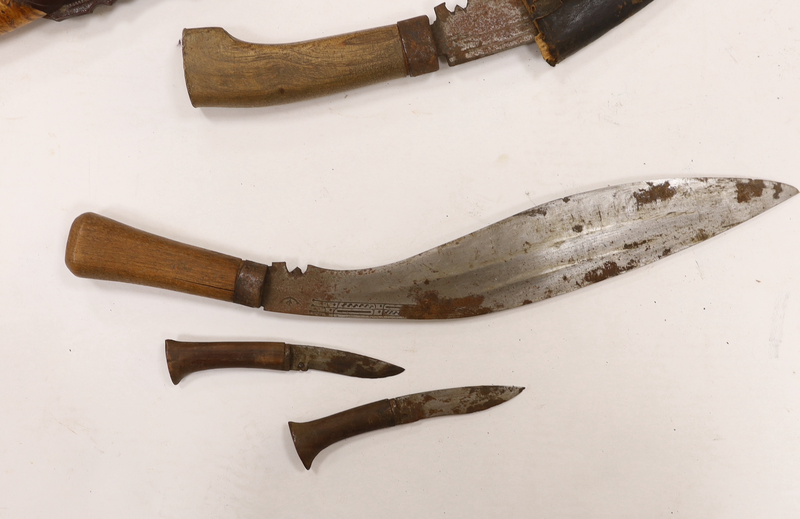 A large Finnish hunting knife, blade dated 1940 and burr wooden handle in its leather sheath, and two Indian kukri in their sheaths
